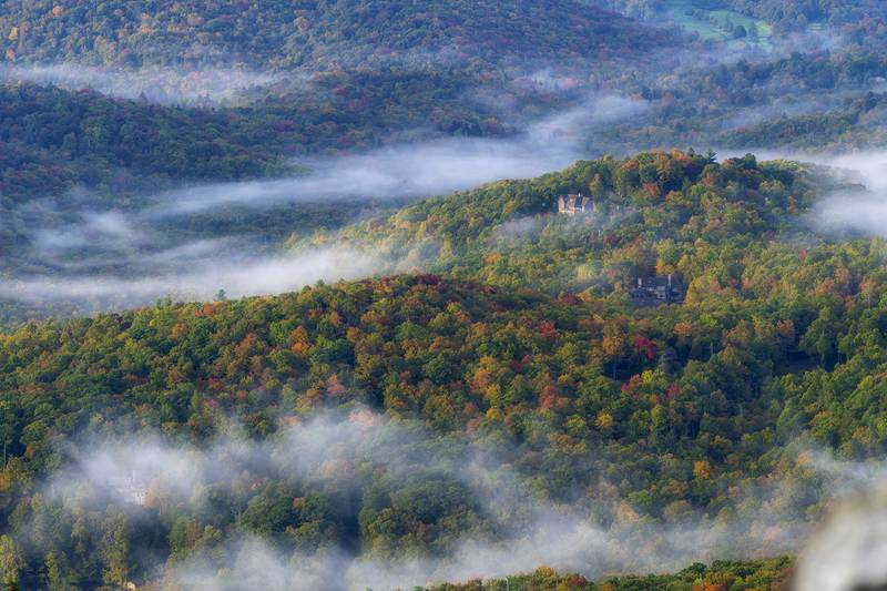 An early morning break in the clouds offers stunning views of color-dappled hills and valleys, as seen from atop Grandfather Mountain’s Linville Peak and the Mile High Swinging Bridge.