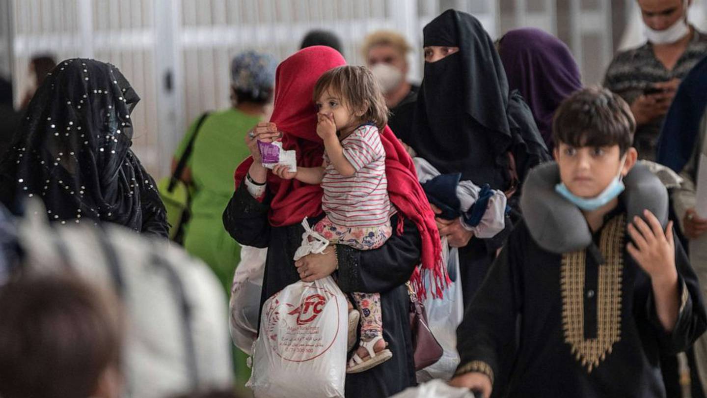 Refugees from Afghanistan are escorted to a waiting bus after arriving and being processed at Dulles International Airport in Dulles, Va. on Aug. 23, 2021.