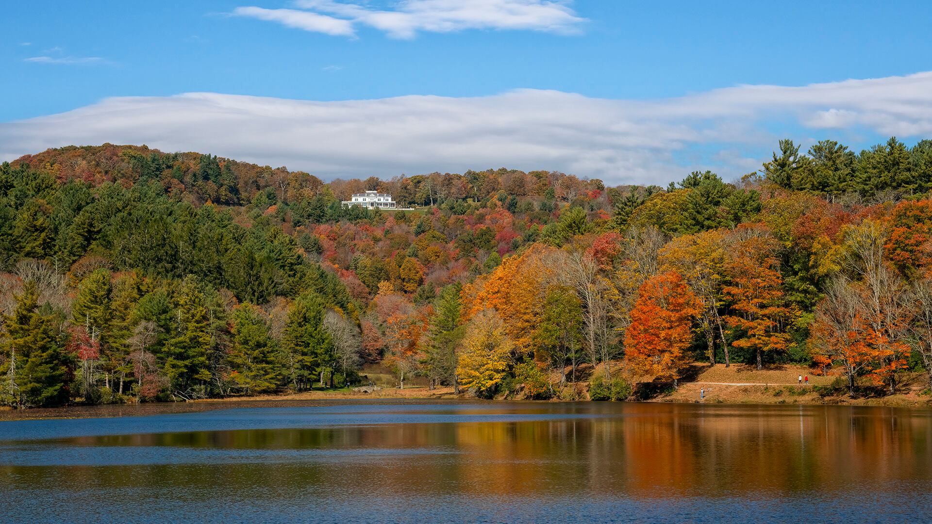 Historic Cone Manor rests above Bass Lake in Blowing Rock, as fall color beams from the shoreline and hillsides.