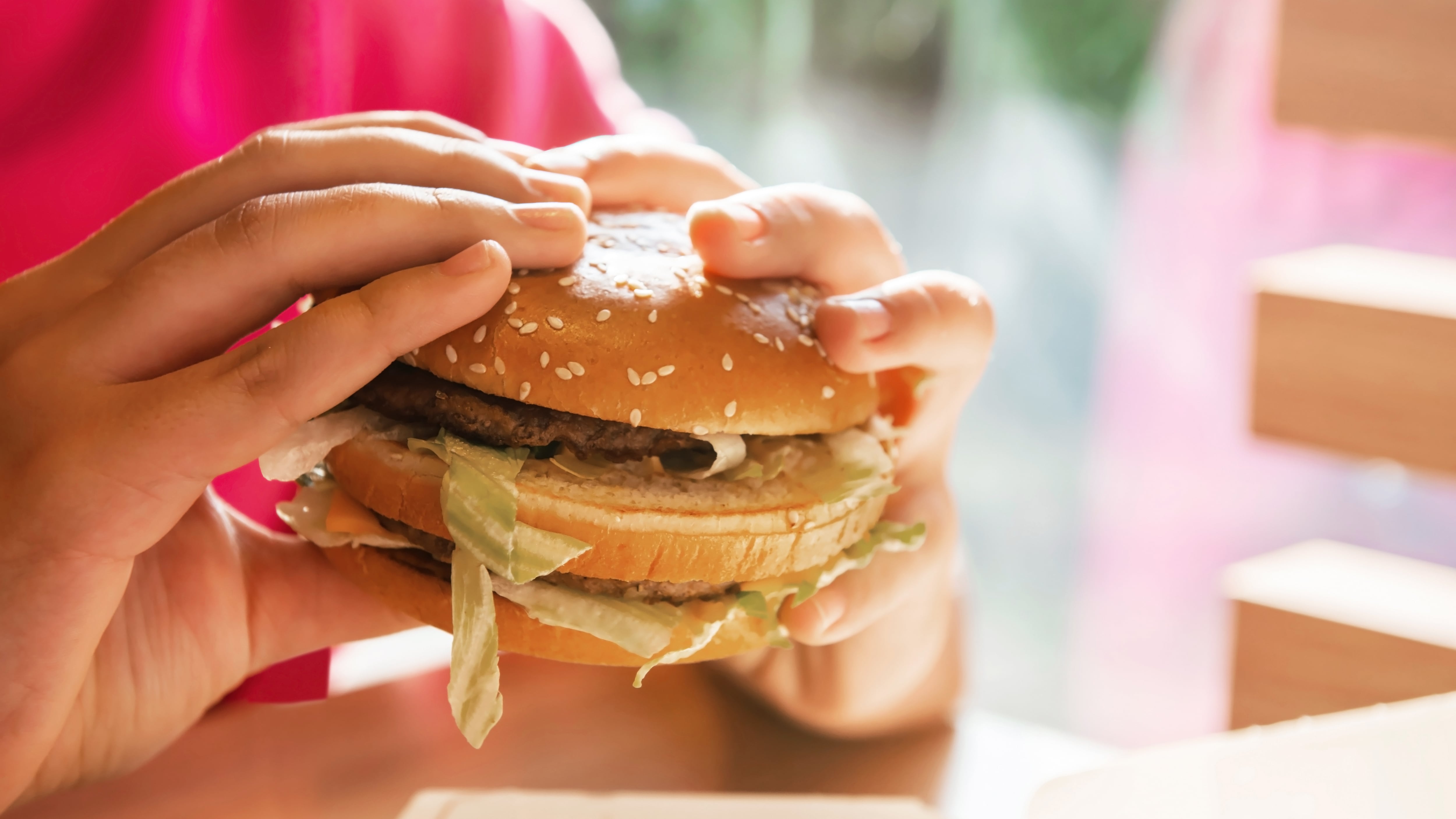 Woman with McDonald's Big Mac at table in cafe, closeup