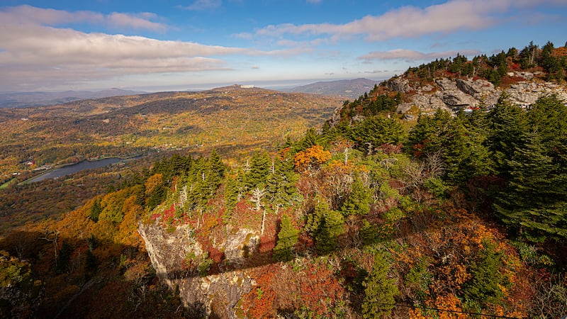 Oct. 10, 2022: The shadow of the Mile High Swinging Bridge appears on a canvas of fall color at the top of Grandfather Mountain. A long (and continuing span) of sunny days and chilly nights have made the colors progress quickly and the mountainsides beautiful. This is the “peak week” for colors at Grandfather Mountain and surrounding areas.