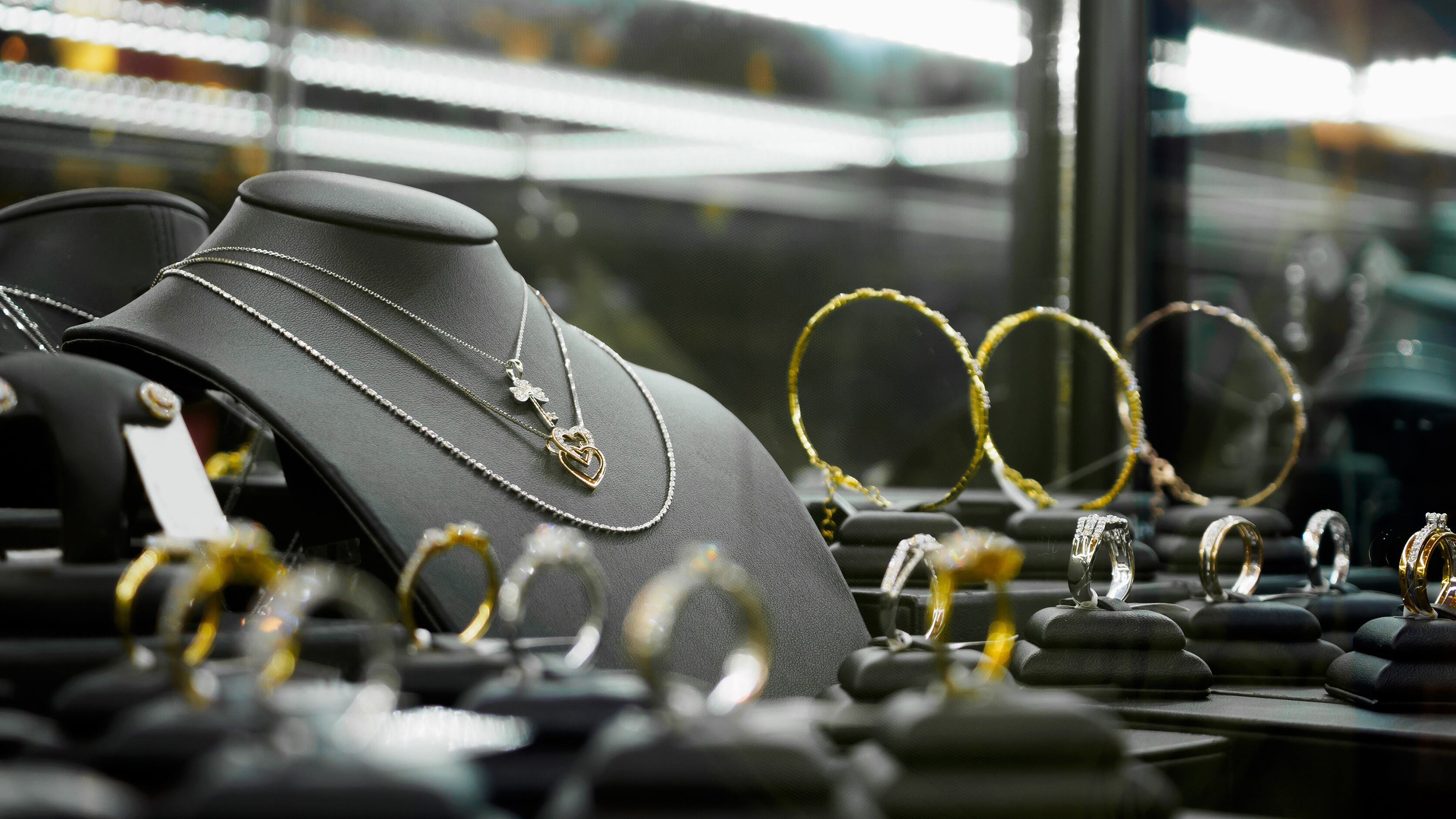 Gold jewelry diamond shop with rings and heart shape necklaces in luxury retail store window display showcase