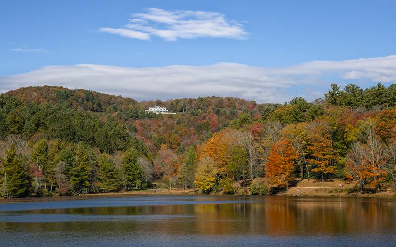 Historic Cone Manor rests above Bass Lake in Blowing Rock, as fall color beams from the shoreline and hillsides.