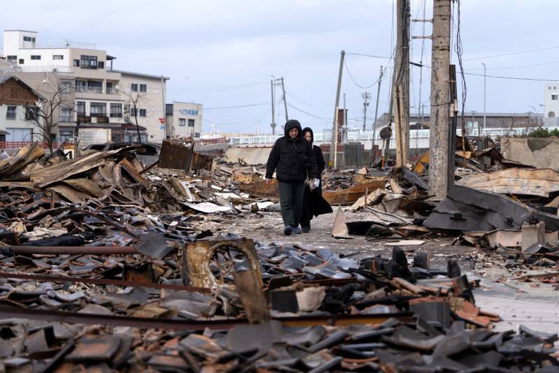 WAJIMA, JAPAN - JANUARY 05: A couple walks through the Asaichi Yokocho, or Wajima Morning Market, area after a fire incident following an earthquake on January 05, 2024 in Wajima, Japan. On New Year's Day, a series of major earthquakes reportedly killed at least 92 people, injured dozens more and destroyed a large amount of homes. The earthquakes, the biggest measuring 7.1 magnitude, hit the areas around Ishikawa, Toyama and Niigata in central Japan. (Photo by Tomohiro Ohsumi/Getty Images)